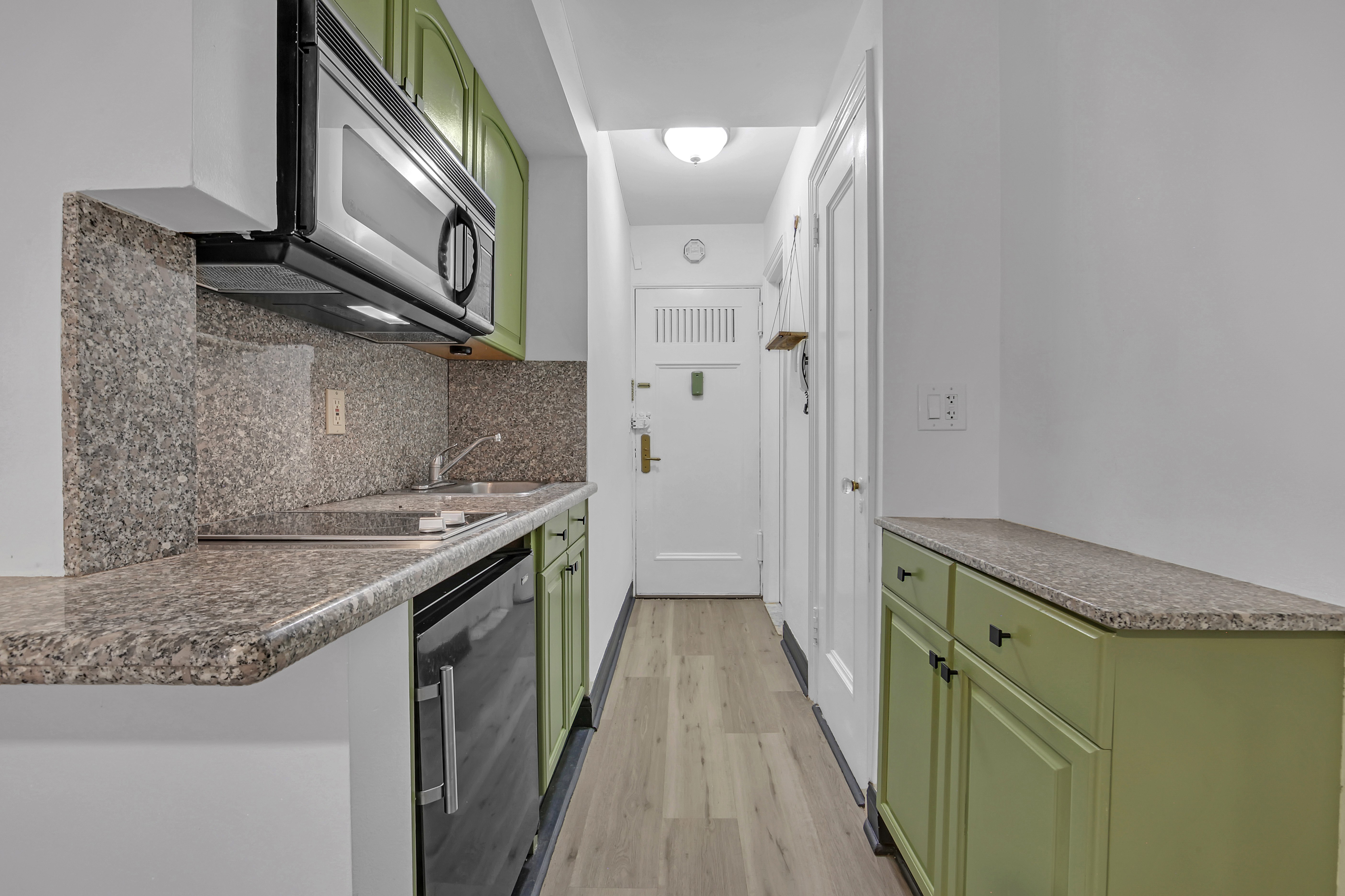 25 Tudor City Place, Unit 1707 Manhattan, NY 10017 - Photo 6 of 18 a kitchen with cabinets and a wooden floor