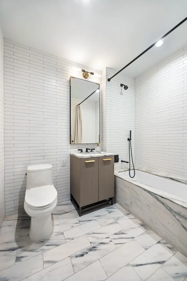a bathroom with a granite countertop toilet a sink and mirror