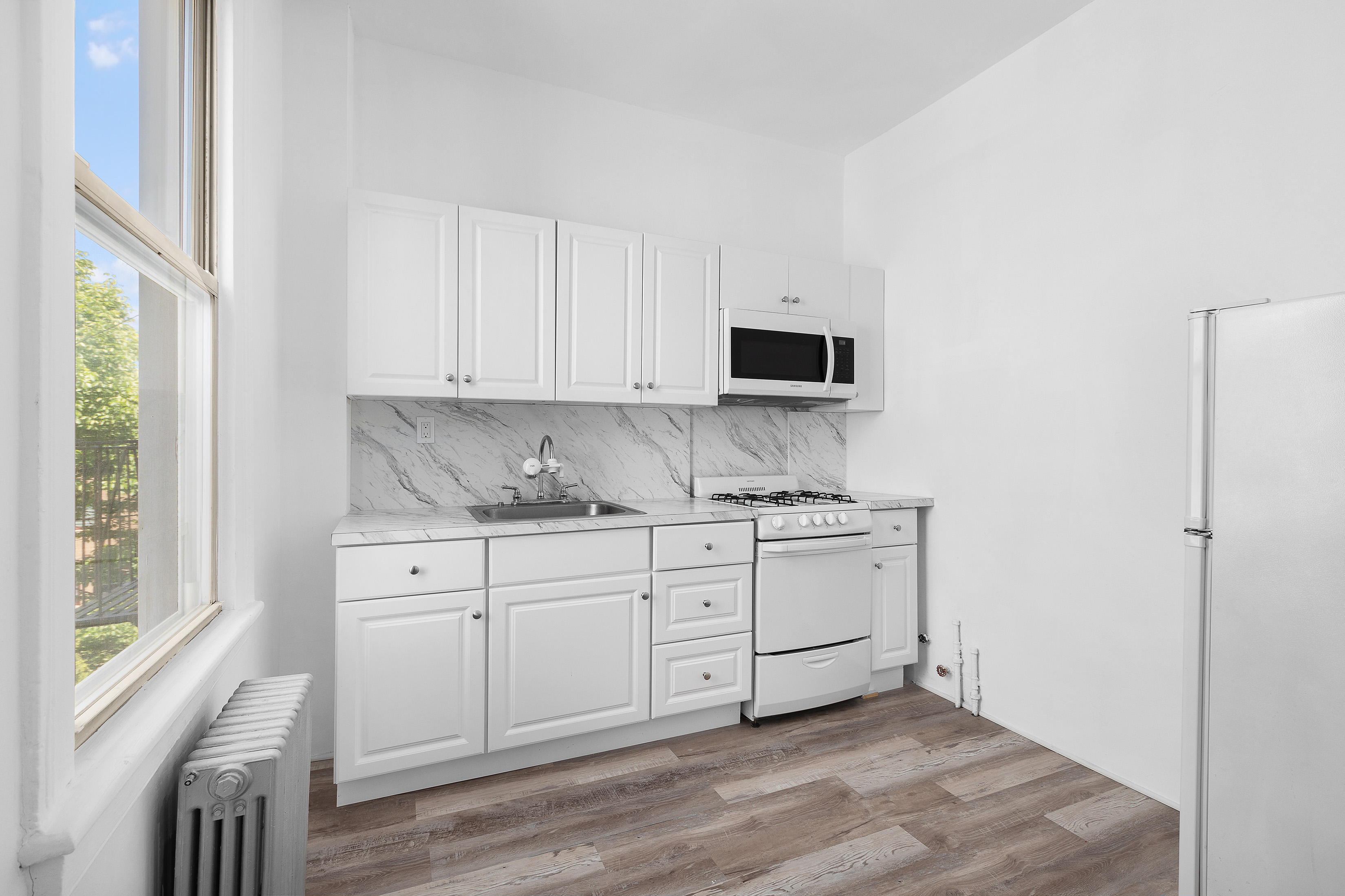 39 Broome Street Brooklyn, NY 11222 - Photo 10 of 16 a kitchen with granite countertop white cabinets and black stainless steel appliances