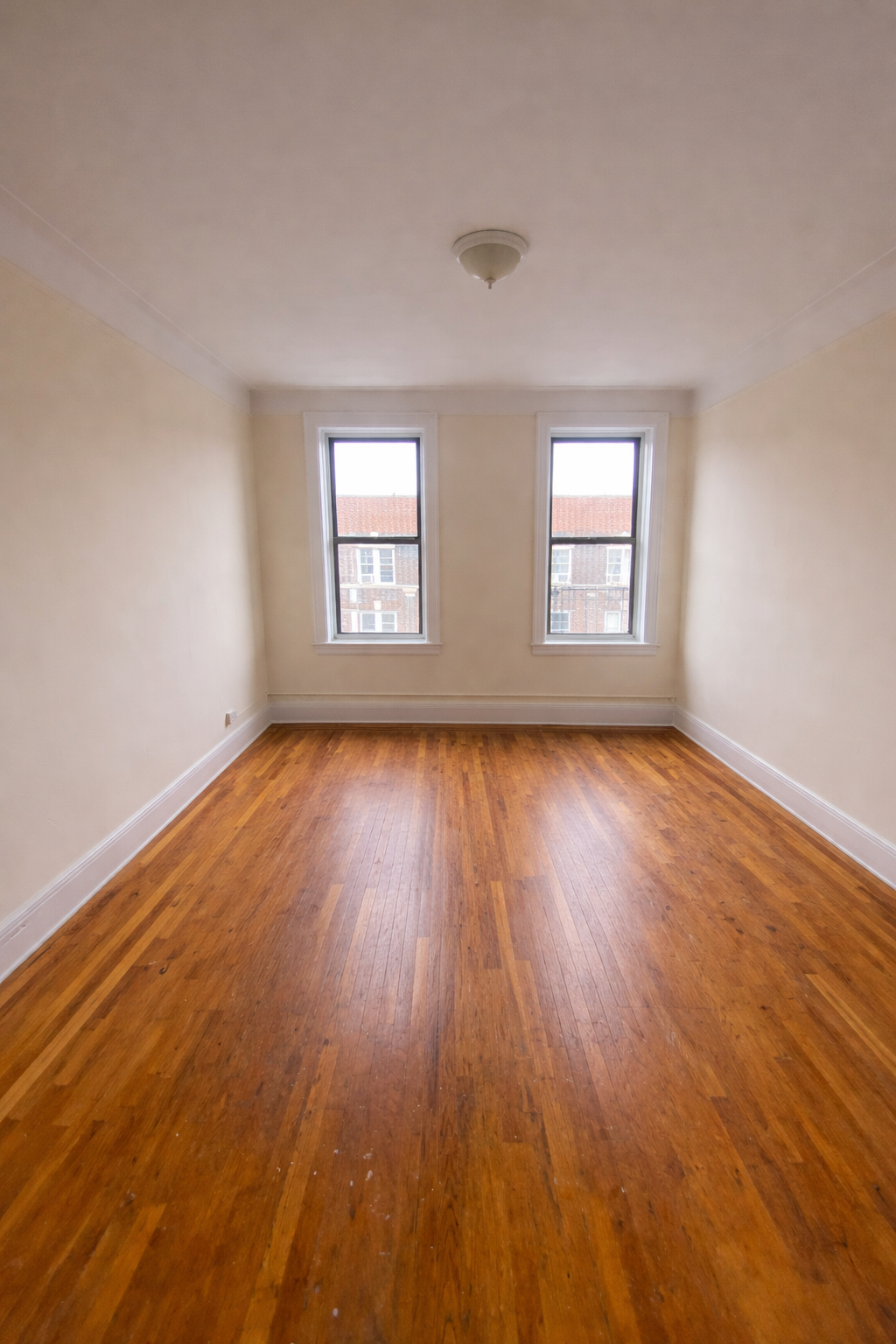 28-23 42nd Street, Unit D5 Queens, NY 11103 - Photo 7 of 10 a view of an empty room with wooden floor and window