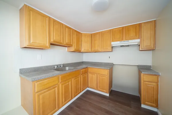 a kitchen with stainless steel appliances granite countertop wooden cabinets a sink and dishwasher with wooden floor