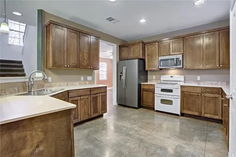 a kitchen with granite countertop a refrigerator stove top oven a sink and dishwasher