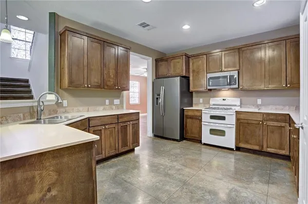 a kitchen with granite countertop a refrigerator stove top oven a sink and dishwasher