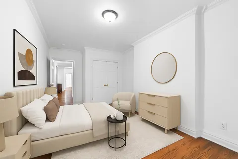 a bedroom with a bed wooden floor and white cabinet
