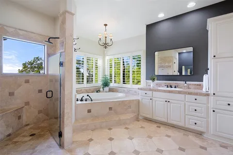 a spacious bathroom with a granite countertop sink mirror and a bathtub