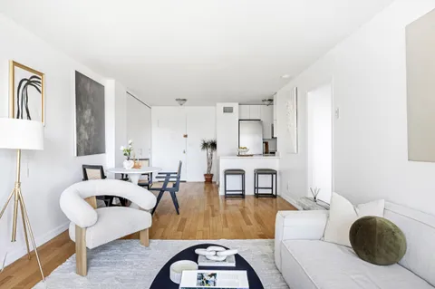 a living room with furniture a rug a lamp and a large window