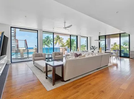 a living room with furniture large windows and wooden floor