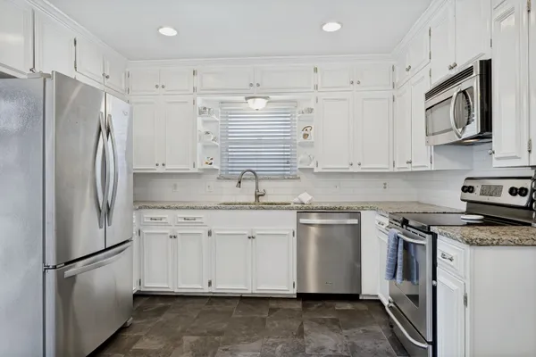a kitchen with stainless steel appliances granite countertop a refrigerator sink and stove
