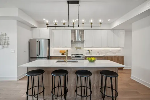 a kitchen with stainless steel appliances kitchen island granite countertop a dining table chairs and white cabinets