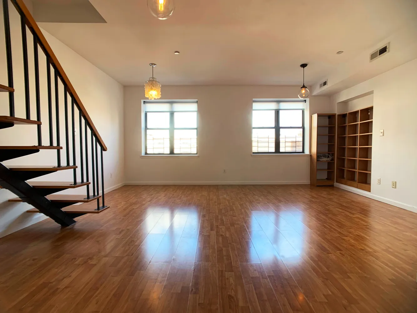 an empty room with wooden floor and windows
