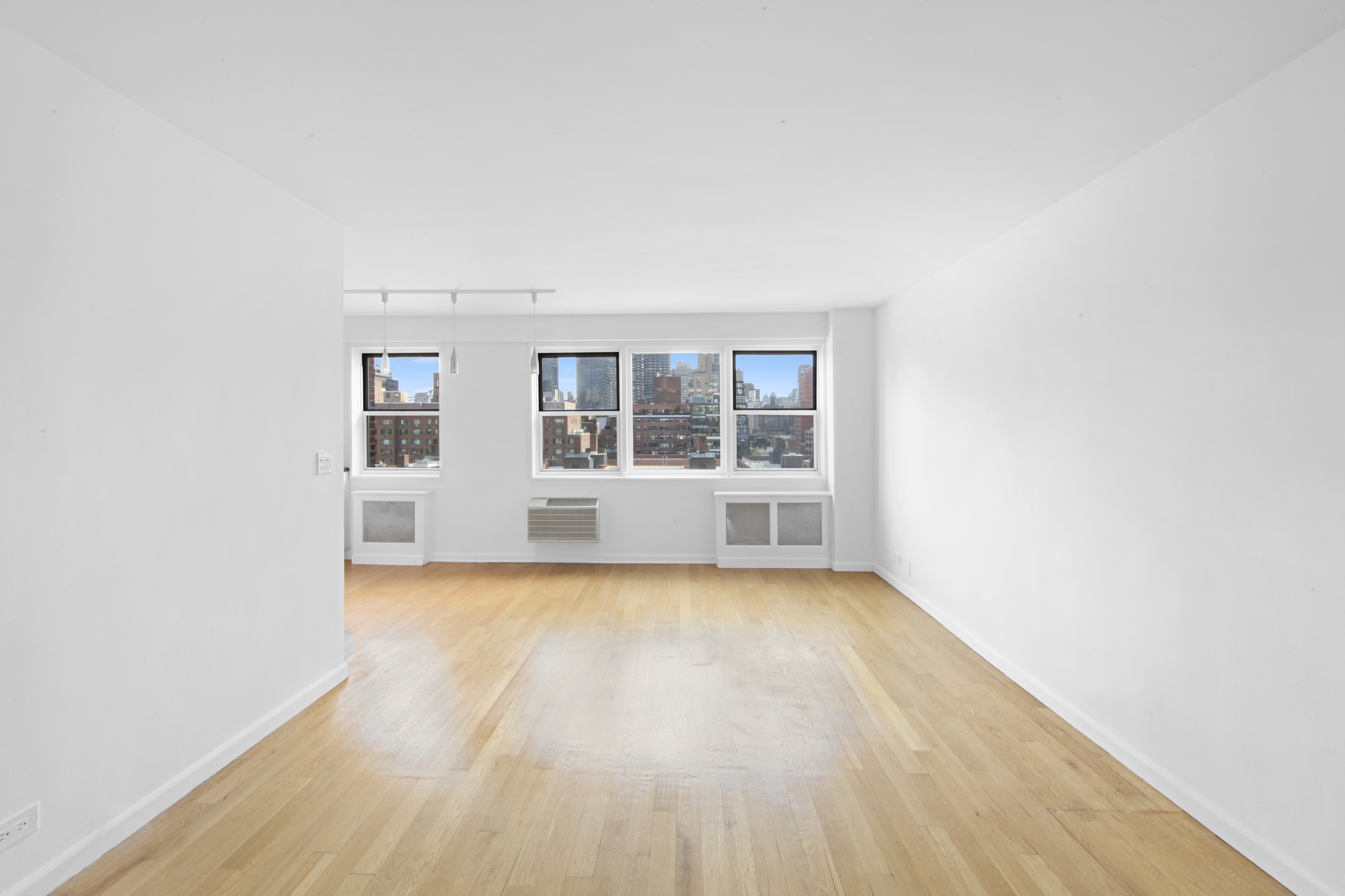 404 East 66th Street, Unit 11B Manhattan, NY 10065 - Photo 2 of 9 an empty room with wooden floor and windows