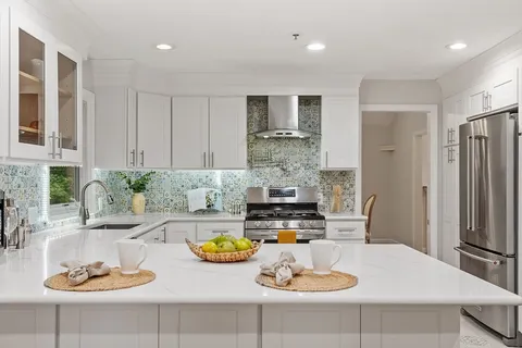 a kitchen with stainless steel appliances a table and chairs in it