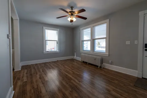 an empty room with wooden floor and windows