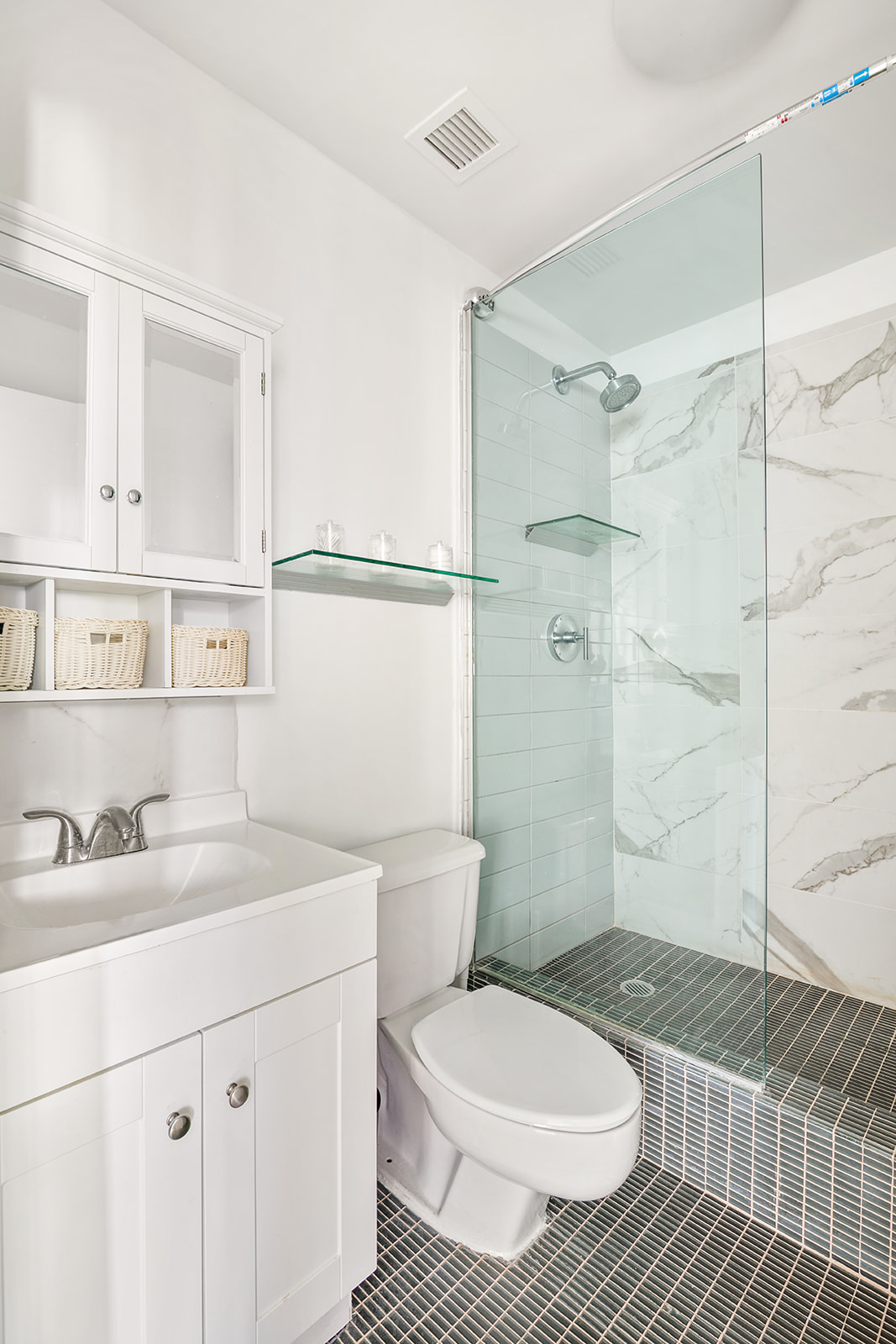 167 Perry Street, Unit 5K Manhattan, NY 10014 - Photo 6 of 10 a bathroom with a sink toilet a mirror and shower