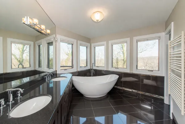 a bathroom with a granite countertop sink a large mirror a bathtub and next to a window