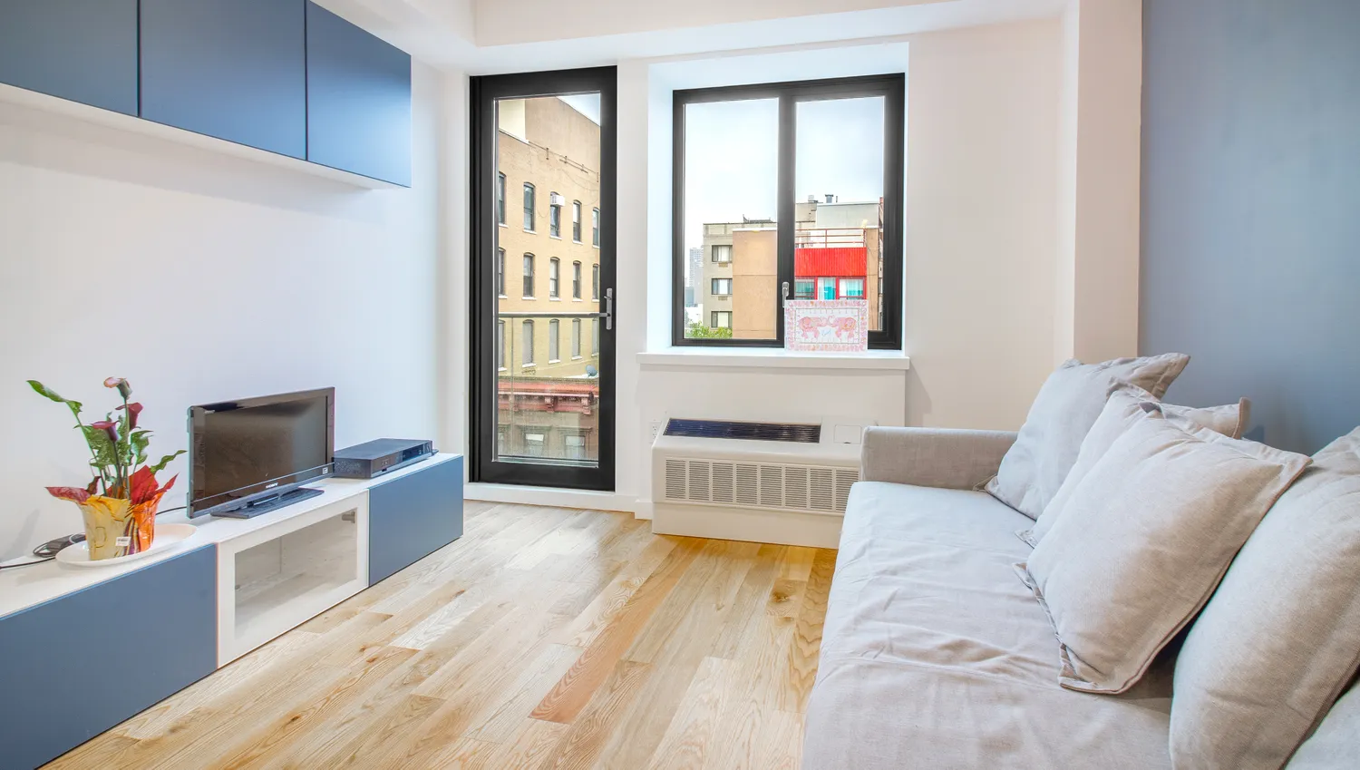 a living room with furniture a flat screen tv and a floor to ceiling window
