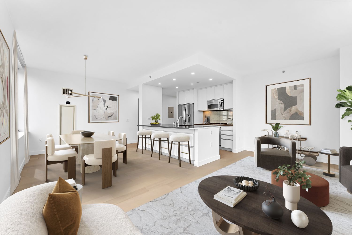 a living room with couches a coffee table and kitchen view with wooden floor