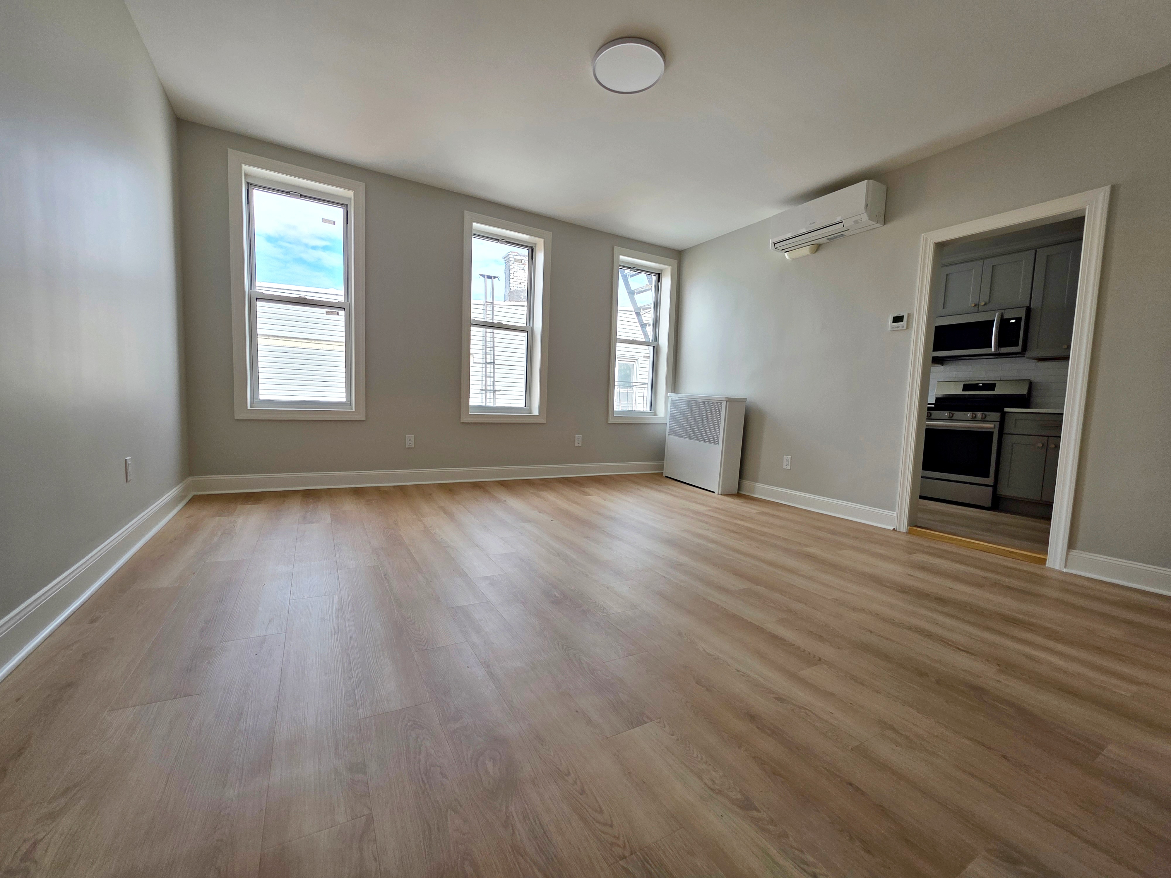 733 Metropolitan Avenue, Unit 3 Brooklyn, NY 11211 - Photo 7 of 13 an empty room with wooden floor and windows