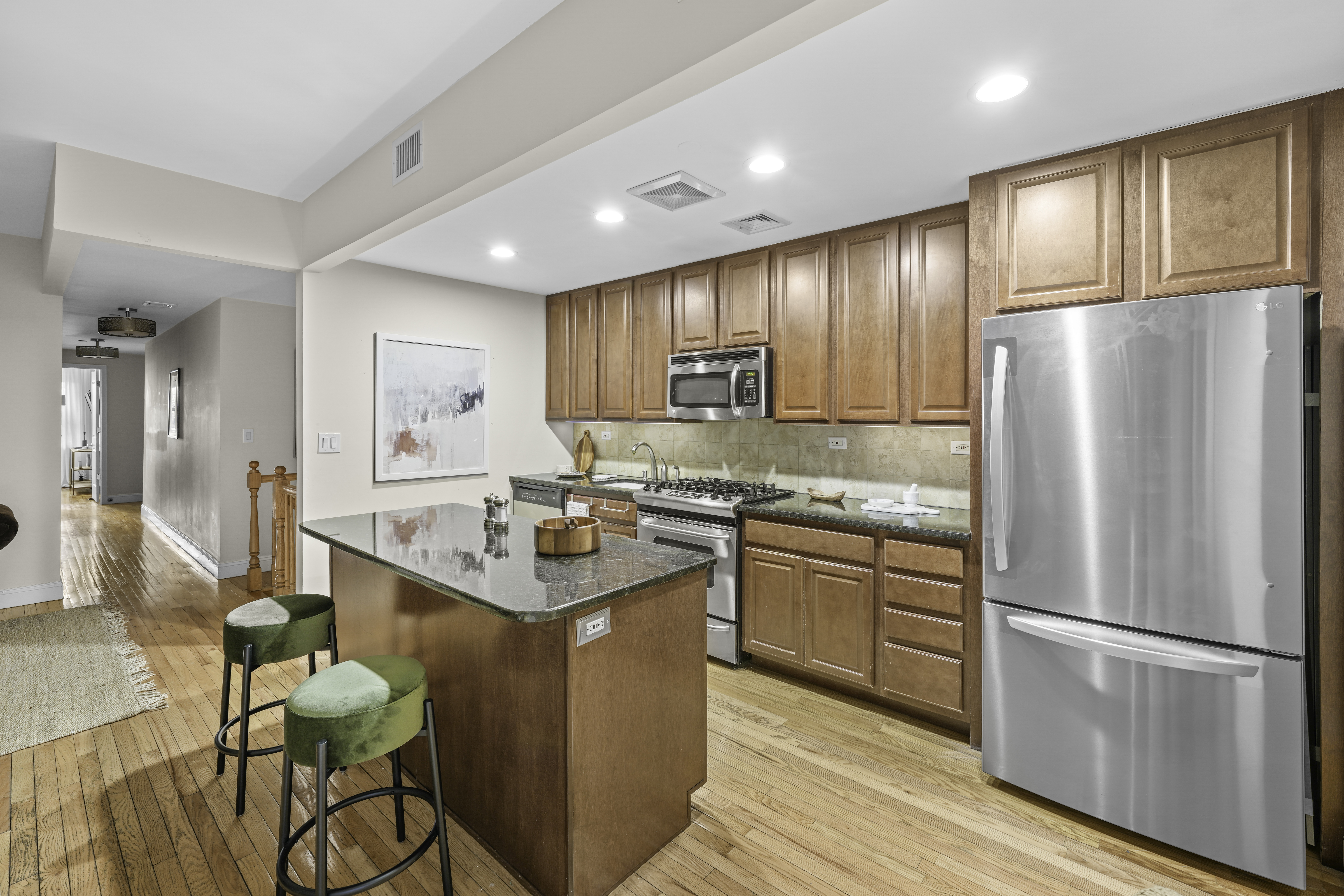 714 St Nicholas Avenue, Unit 1 Manhattan, NY 10031 - Photo 11 of 18 a kitchen with stainless steel appliances granite countertop a refrigerator a sink dishwasher a stove and white countertops with wooden floor