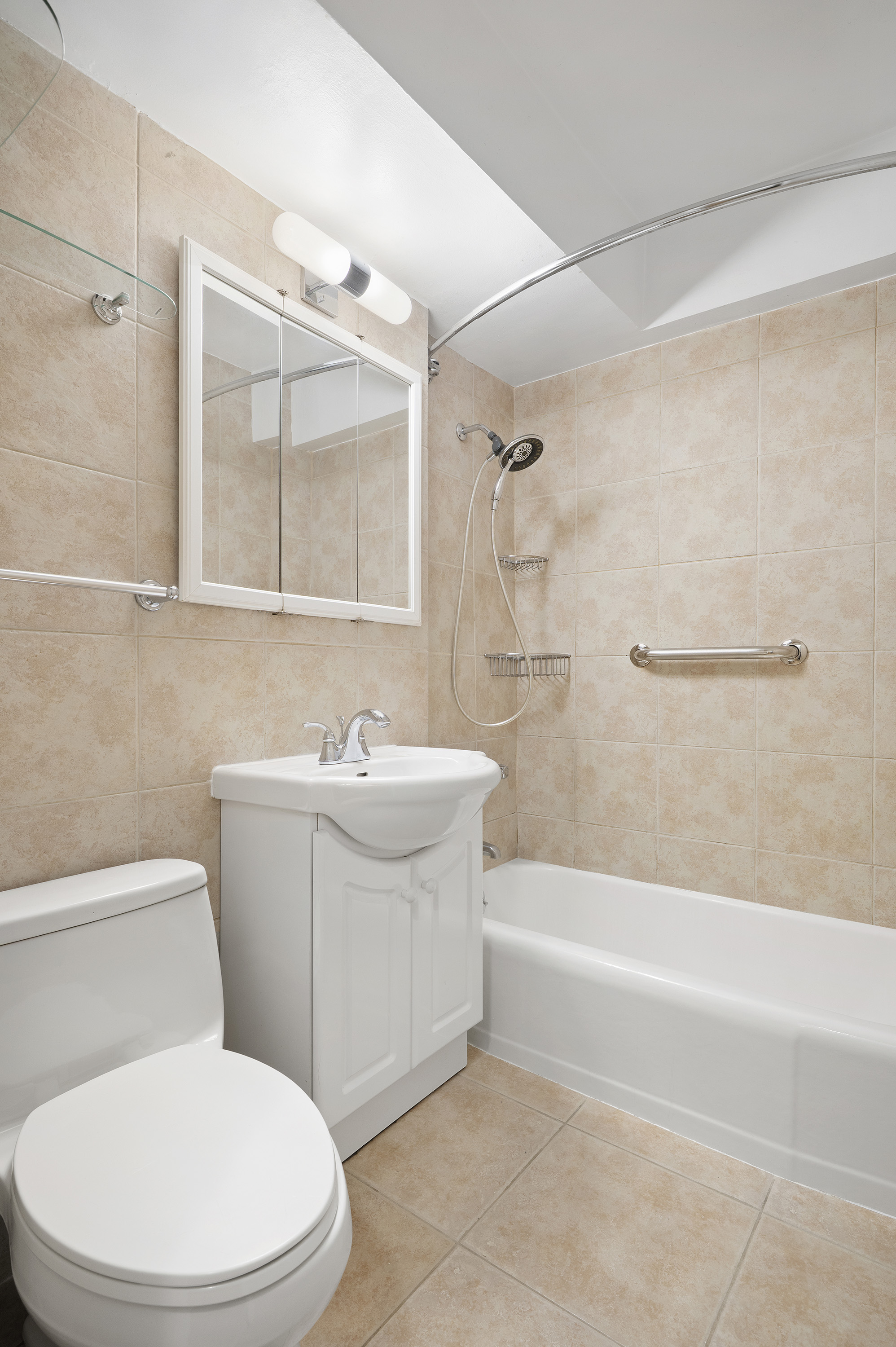 153 East 57th Street, Unit 8J Manhattan, NY 10022 - Photo 4 of 8 a bathroom with a toilet a sink a mirror and bathtub