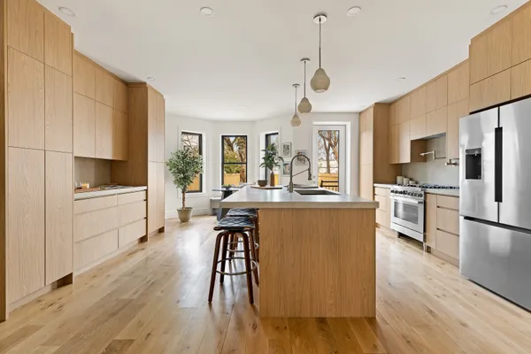 a kitchen with stainless steel appliances a stove a sink a refrigerator a center island and wooden floor