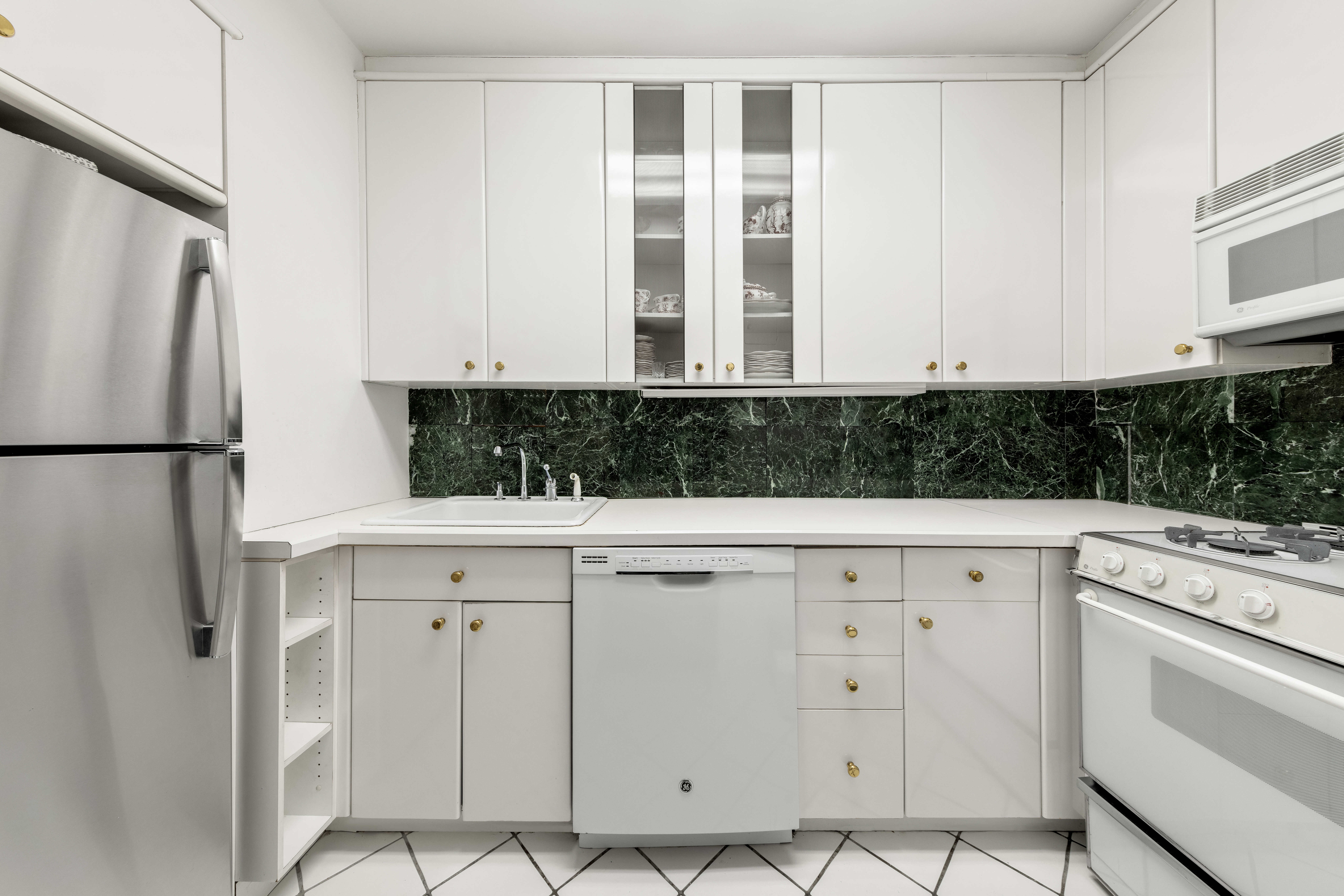 25 Sutton Place South, Unit 18L Manhattan, NY 10022 - Photo 3 of 11 a view of cabinets with stainless steel appliances granite countertop white cabinets and window
