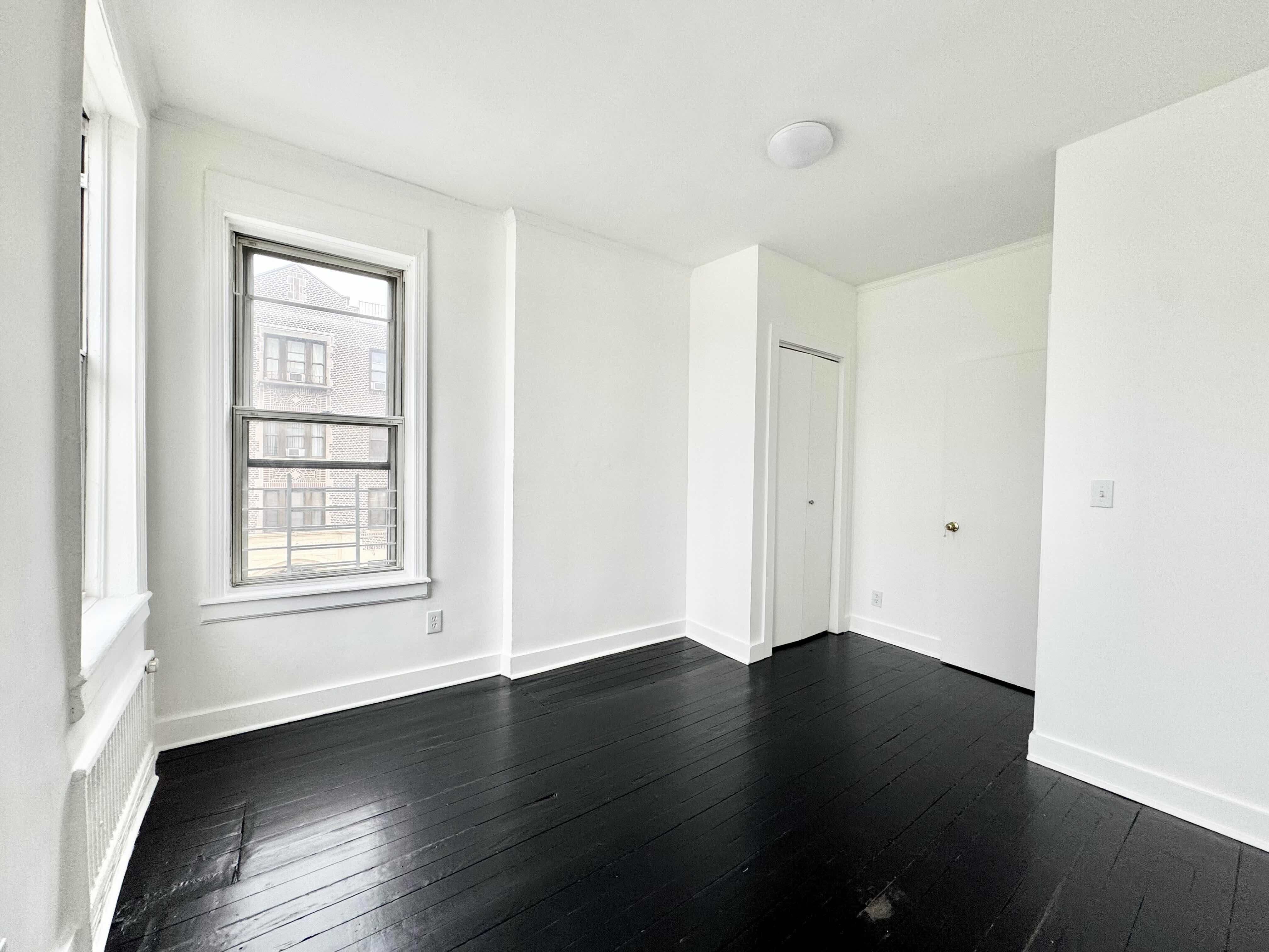 406 Rogers Avenue, Unit 3 Brooklyn, NY 11225 - Photo 8 of 9 a view of an empty room with wooden floor and a window