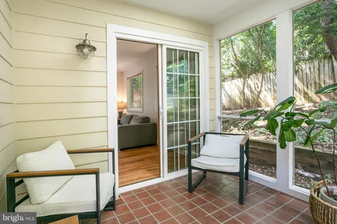 a porch with a bench and a potted plant