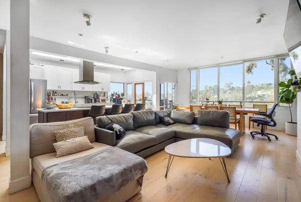 a living room with furniture kitchen view and large windows