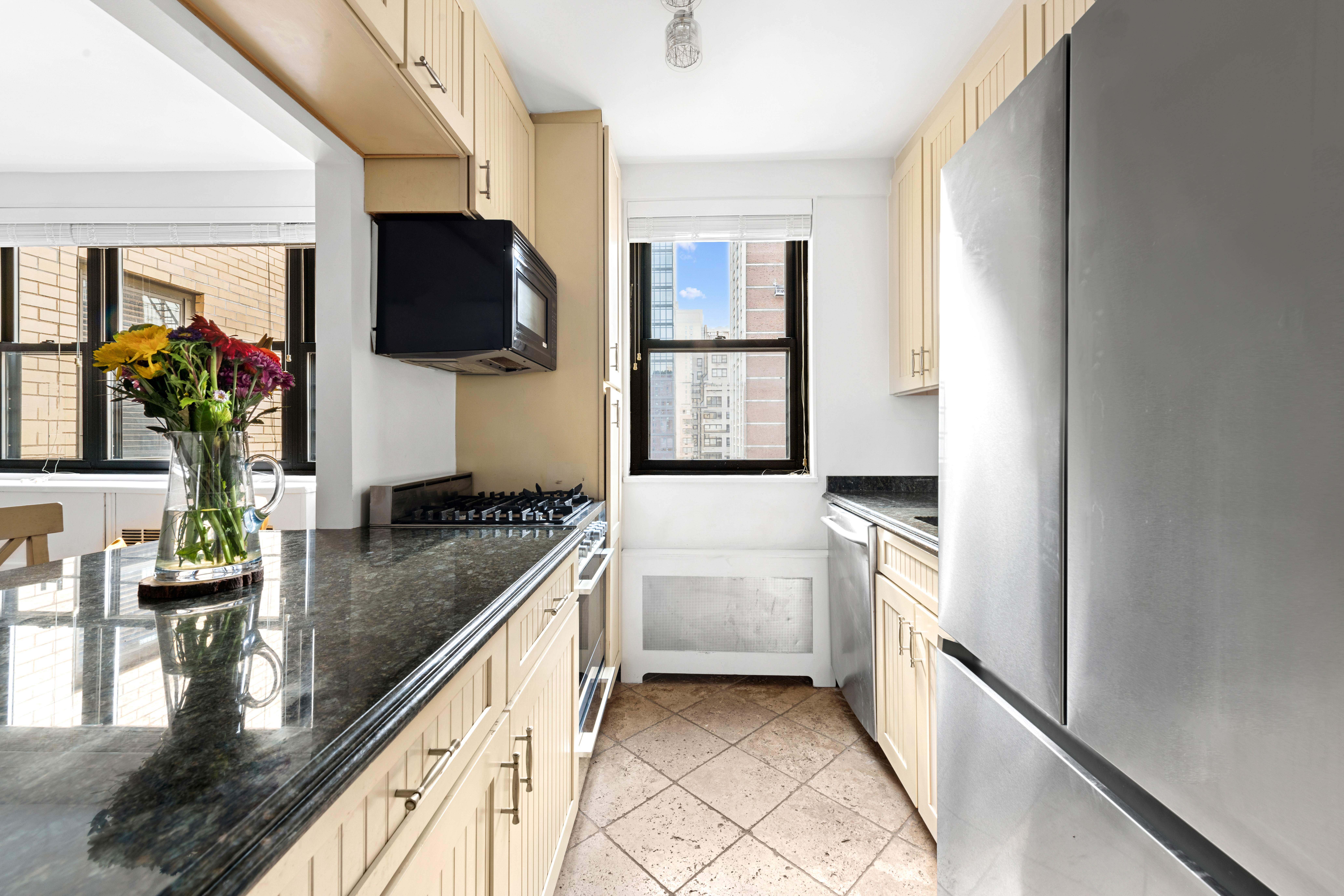 315 East 72nd Street, Unit 15M Manhattan, NY 10021 - Photo 7 of 18 a kitchen with stainless steel appliances granite countertop a sink and a stove