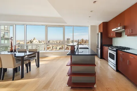 a living room with couches and kitchen view with wooden floor