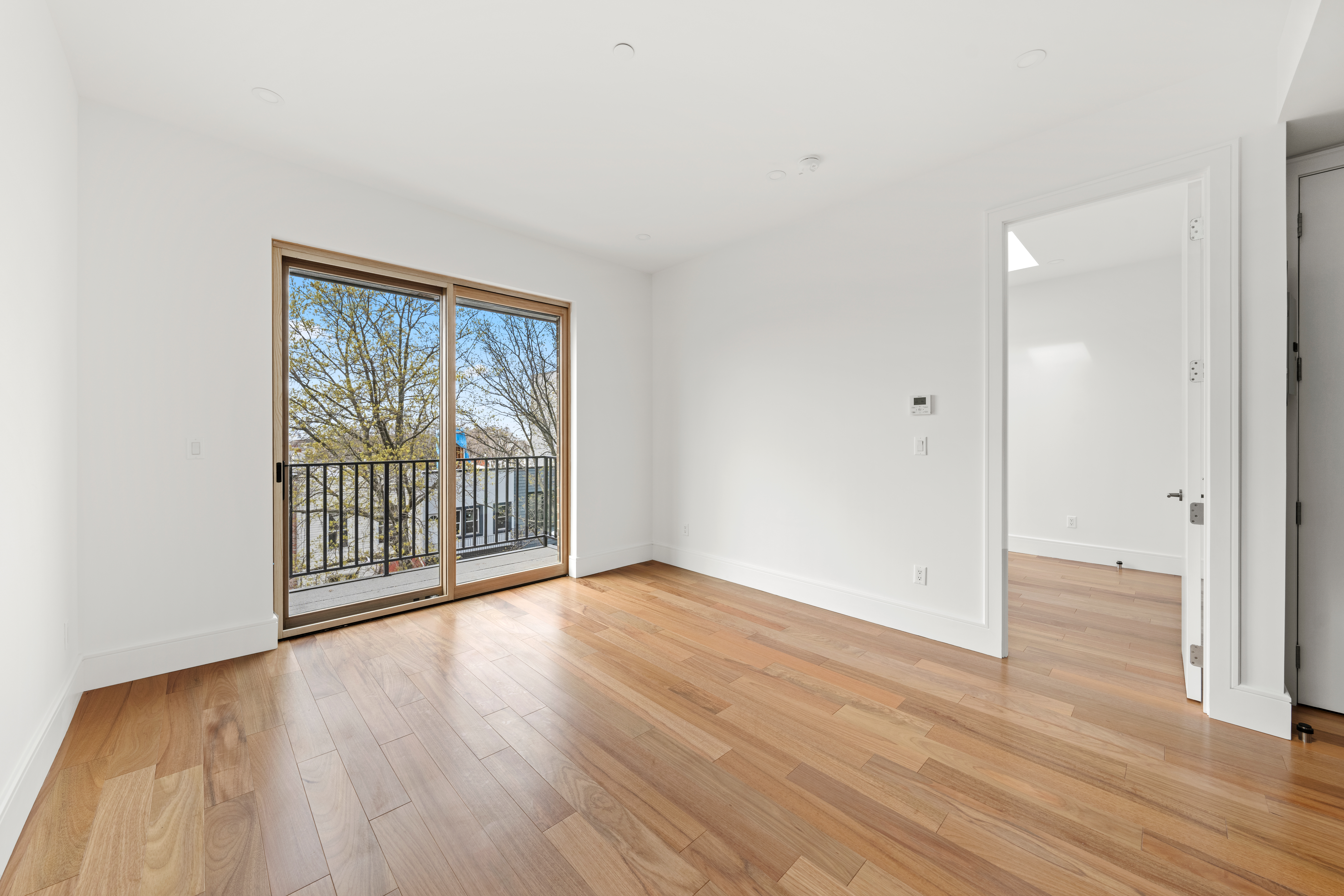 82 Cooper Street, Unit 3A Brooklyn, NY 11207 - Photo 6 of 17 a view of an empty room with wooden floor and a window