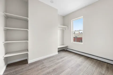 a view of an empty room with a window and wooden floor