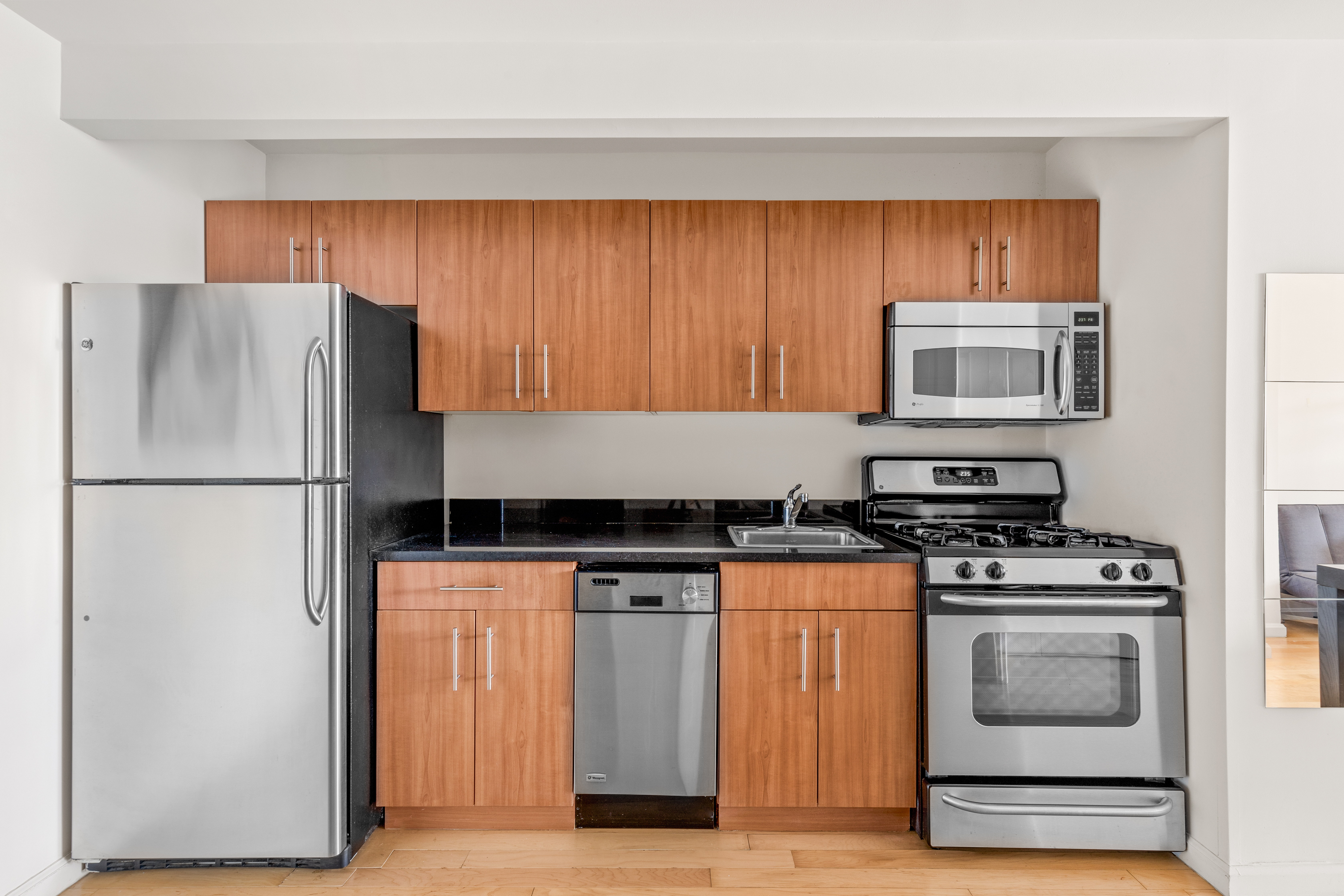 20 West Street, Unit 31C Manhattan, NY 10004 - Photo 5 of 16 a kitchen with granite countertop a refrigerator stove and microwave