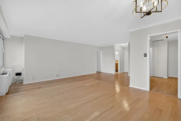 a view of an empty room with wooden floor and windows