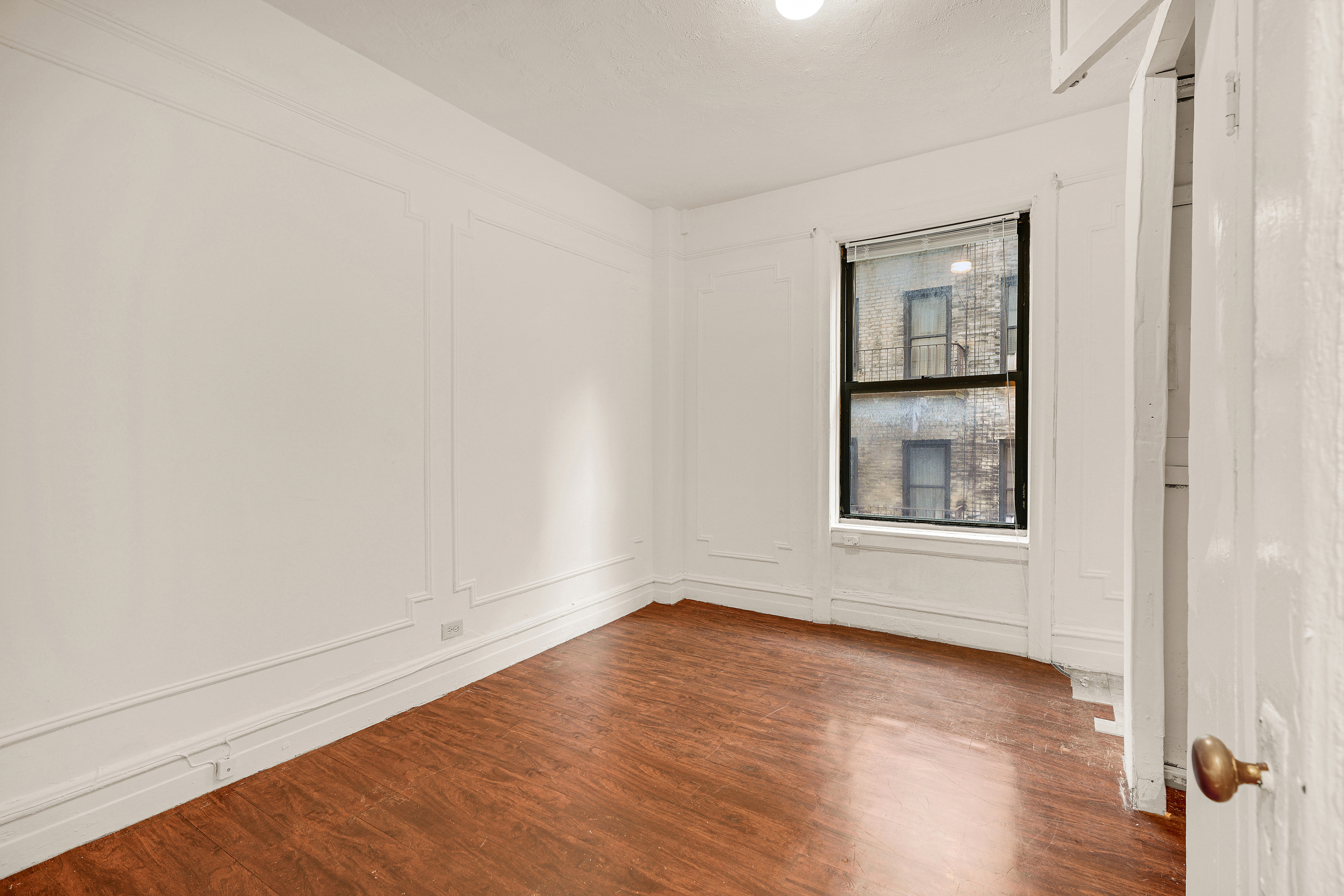 544 West 157th Street, Unit 44 Manhattan, NY 10032 - Photo 6 of 9 a view of an empty room with wooden floor and a window