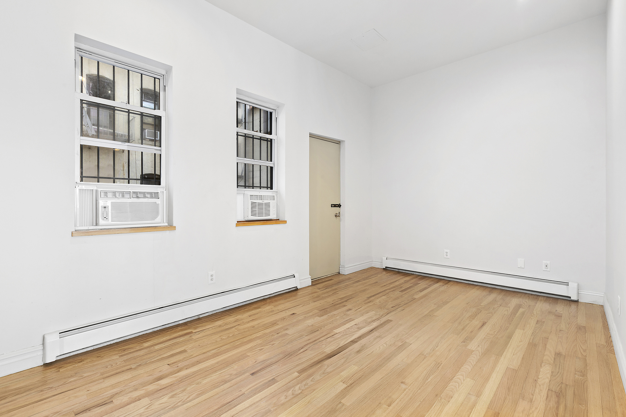85 Division Street, Unit 4 Manhattan, NY 10002 - Photo 4 of 22 a view of empty room with wooden floor and fan