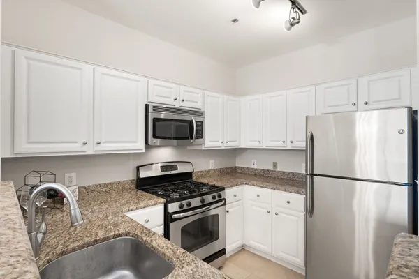 a kitchen with stainless steel appliances granite countertop a refrigerator sink and stove