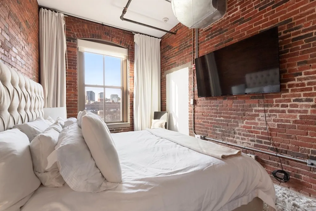 a bedroom with a bed a flat screen tv and a window