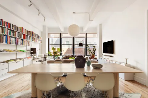 a dining room with wooden floor and large windows