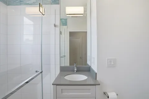 a bathroom with a granite countertop sink a mirror and shower