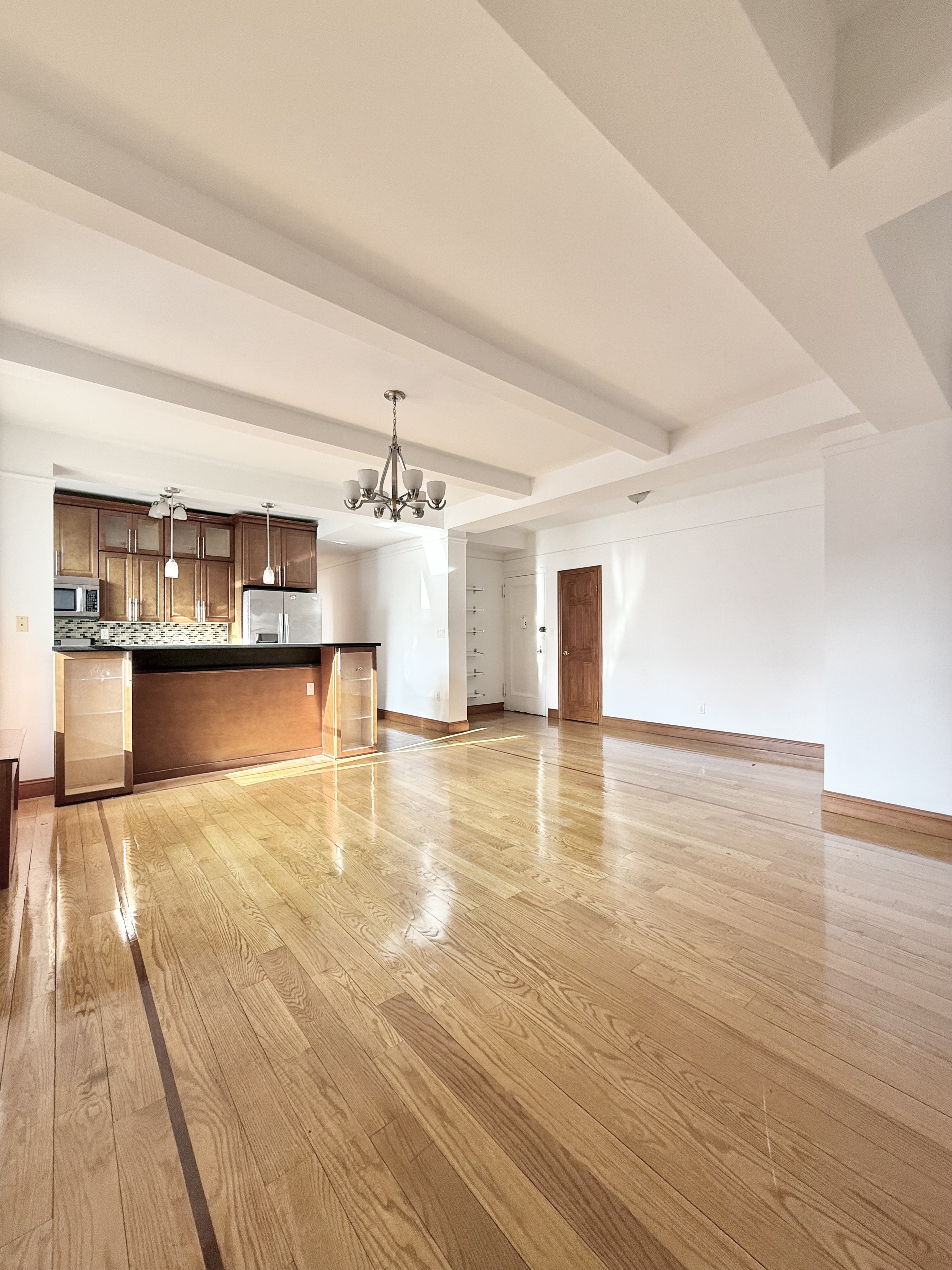 675 West End Avenue, Unit 12A Manhattan, NY 10025 - Photo 2 of 15 a view of a living room with kitchen island stainless steel appliances wooden floor and furniture