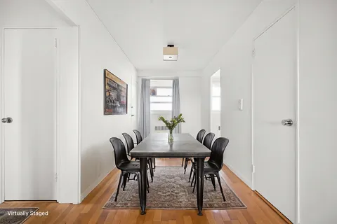 a view of a hallway with wooden floor and a bathroom