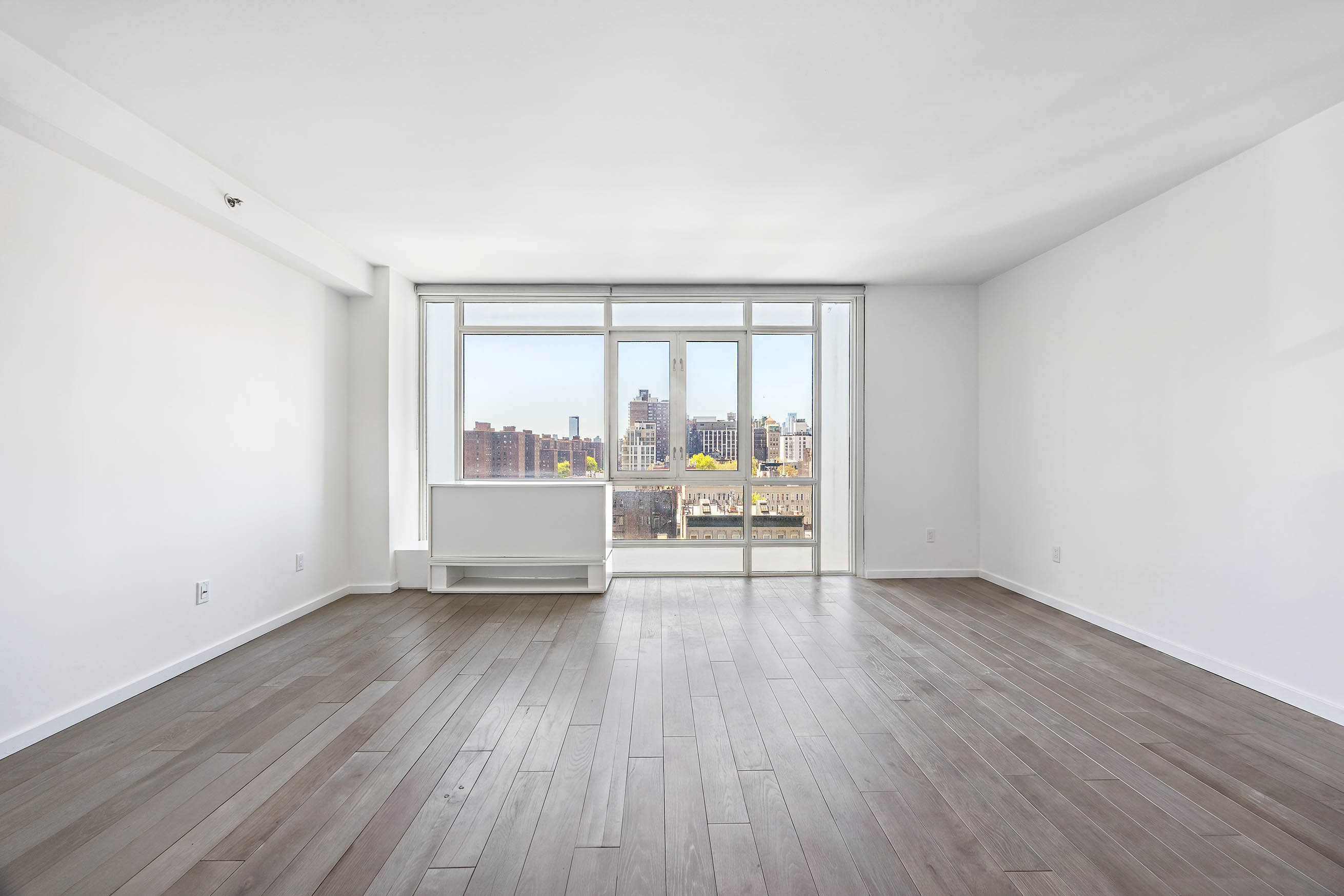 385 1st Avenue, Unit 10A Manhattan, NY 10010 - Photo 2 of 9 an empty room with wooden floor and furniture