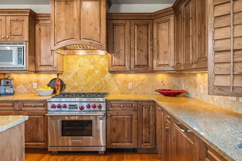 a kitchen with stainless steel appliances granite countertop a stove a sink and a microwave