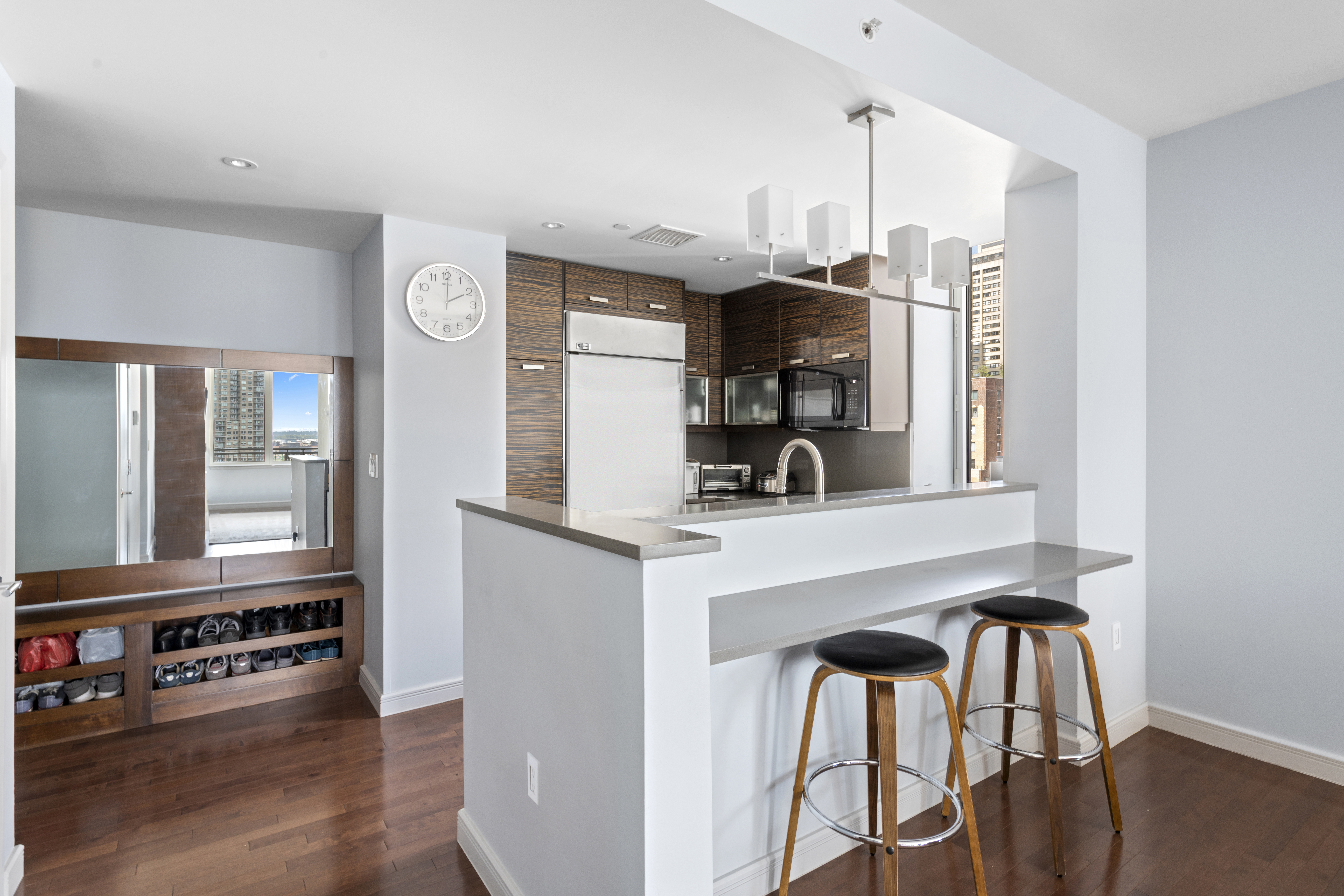 225 East 34th Street, Unit 17B Manhattan, NY 10016 - Photo 3 of 24 a kitchen with stainless steel appliances a table chairs and a refrigerator