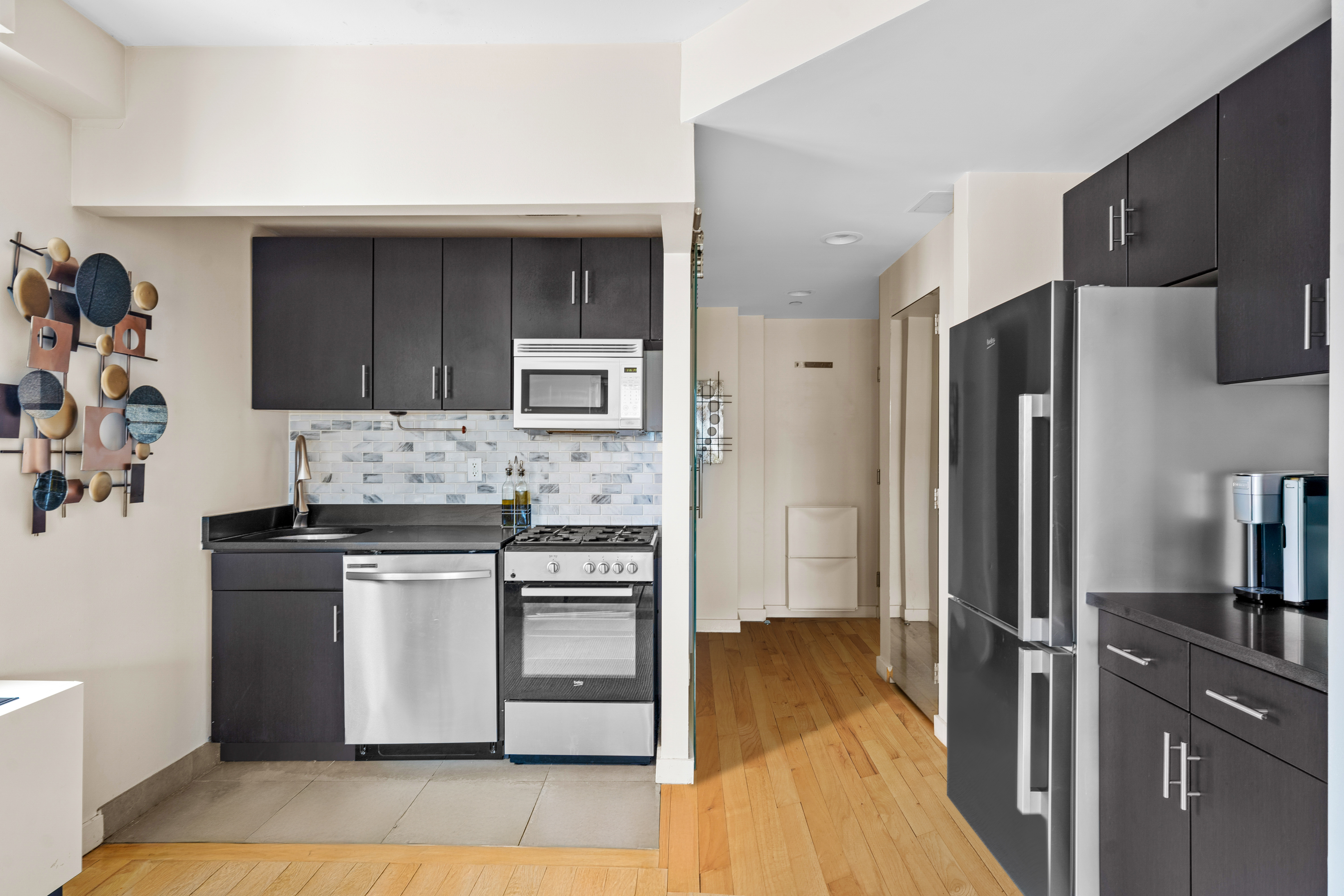 1810 3rd Avenue, Unit A9B Manhattan, NY 10029 - Photo 5 of 16 a kitchen with white cabinets and stainless steel appliances