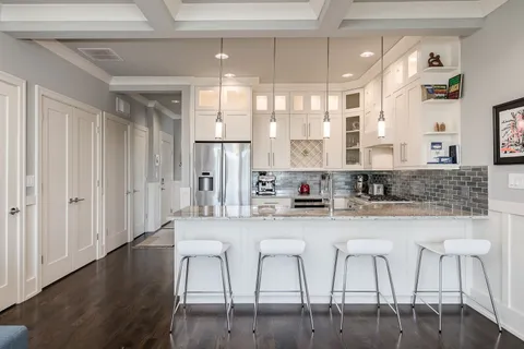 a kitchen with stainless steel appliances granite countertop a table chairs sink and cabinets