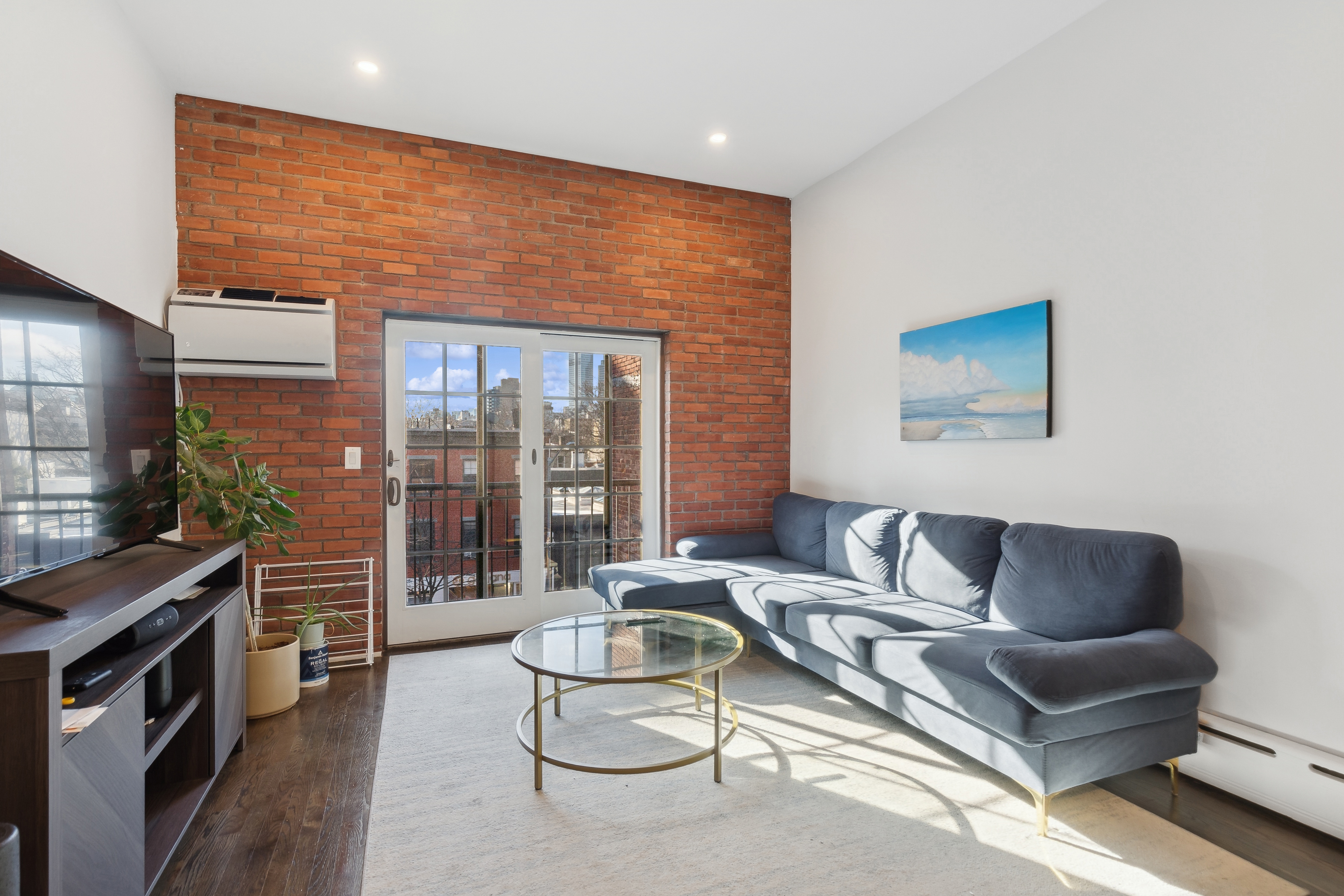 a living room with furniture a flat screen tv and a floor to ceiling window