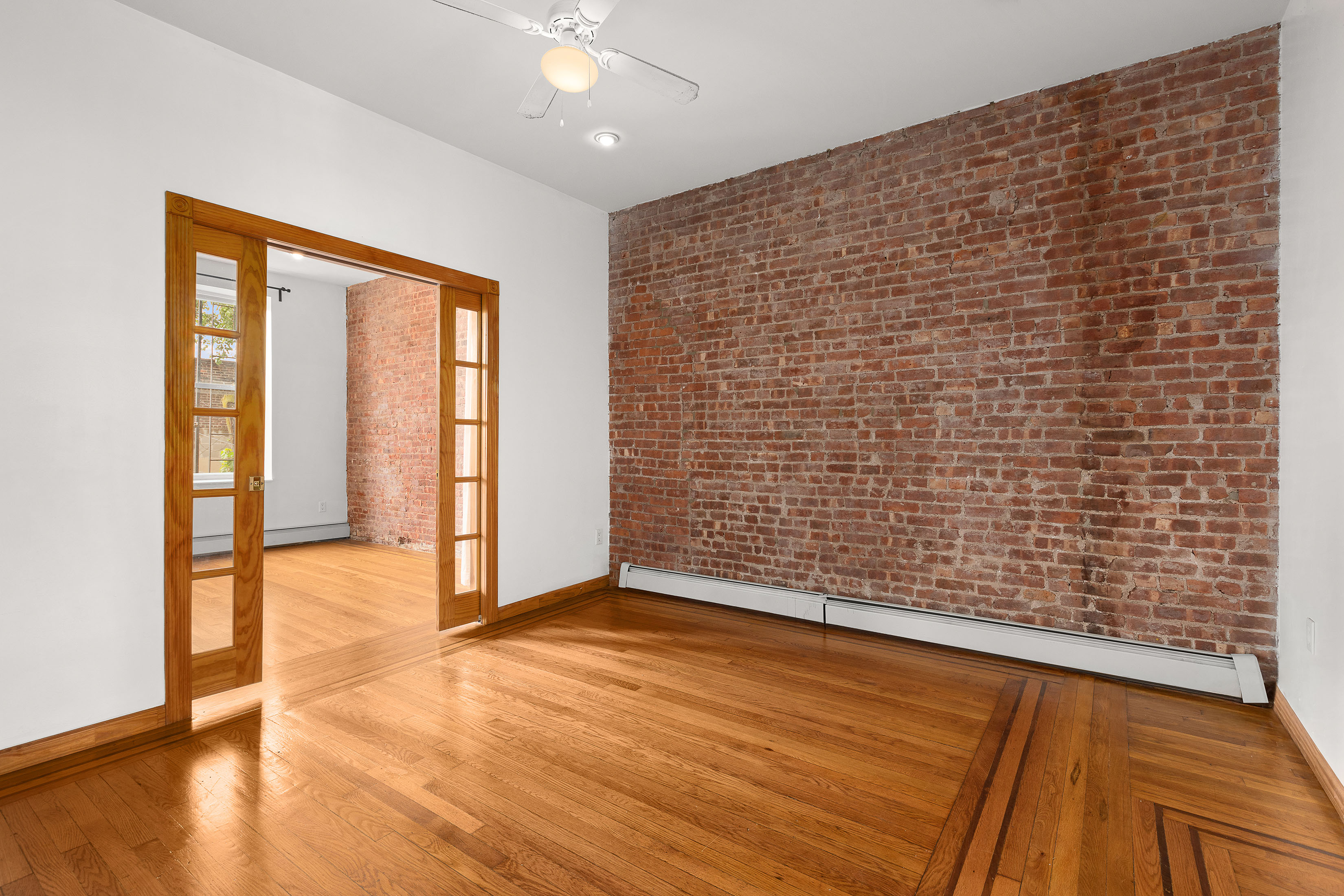 11-51 44th Drive, Unit 2 Queens, NY 11101 - Photo 5 of 6 a view of an empty room with wooden floor and a window